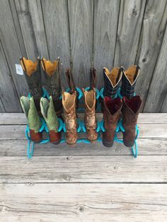 six pairs of boots are lined up on a rack outside, one is brown and the other is blue