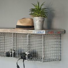 a hat is hanging on a metal shelf next to a potted plant and camera