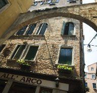 an arch in the side of a building with plants growing on it's windows