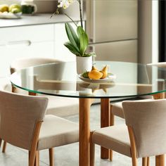 a glass table with chairs around it and a potted plant in the middle on top