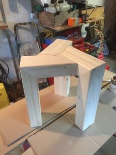 a wooden table sitting on top of a piece of plywood in a room filled with tools