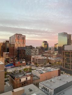 the city is full of tall buildings and skyscrapers as the sun sets in the distance