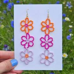 a pair of earrings made out of plastic beads with flowers in the middle, on top of a card