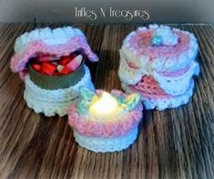 two crocheted baskets with a lit candle in them on a wooden table top