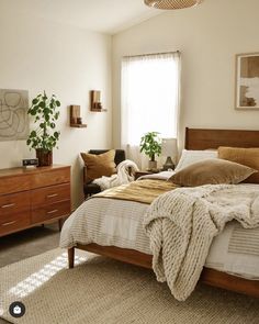 a bed room with a neatly made bed and two plants on the side of the bed