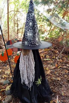 a black witch hat with spider webs on it, sitting in front of a tree