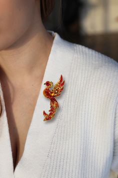 a woman wearing a white sweater and red brooch