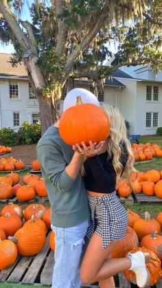 a man and woman standing next to each other in front of pumpkins