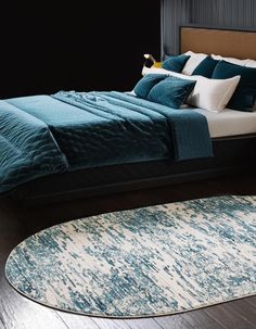 a bed with blue and white pillows on top of it next to a round rug