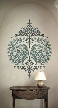 a lamp sitting on top of a table in front of a wall with a peacock decal