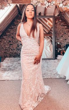 a woman standing in front of a mirror wearing a wedding dress with flowers on it