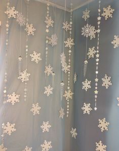 snowflakes are hanging from the ceiling in front of a curtain that is decorated with beads