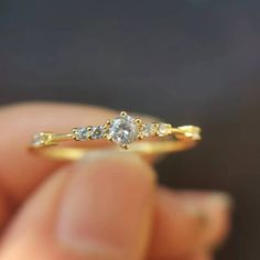 a person holding a yellow gold ring with three stones