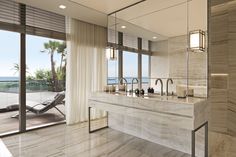 a large bathroom with marble counter tops and double sinks in front of an ocean view