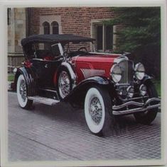 an antique car is parked in front of a brick building