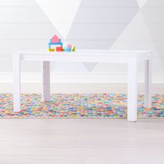 a white table sitting on top of a tiled floor next to a wall with geometric designs