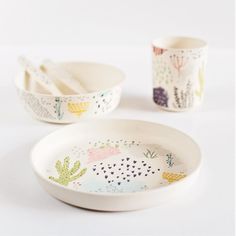 three bowls and two spoons with cactus designs on them, one is white the other is black