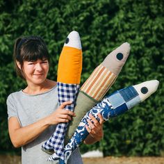 a woman holding three stuffed rockets in her hands