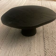 a black wooden table sitting on top of a white carpeted floor next to a bed