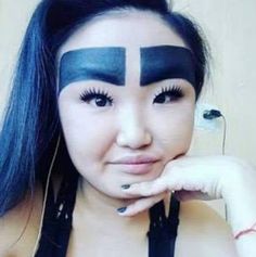 a woman with blue hair and black makeup has her face painted in the shape of a cross