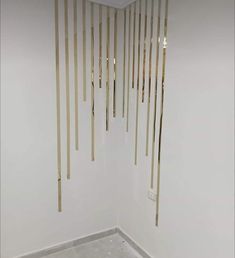 an empty room with white walls and wooden sticks hanging from the ceiling