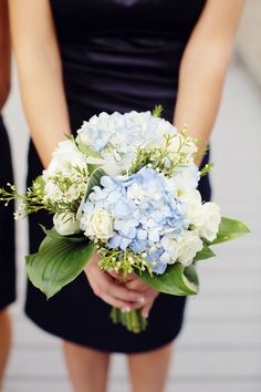 two women in black dresses holding blue and white flowers