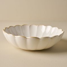 a white bowl sitting on top of a table next to a beige wall and floor