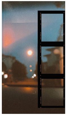 an open window on the side of a building at night with street lights in the background