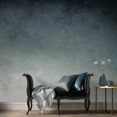 a chair and table in front of a gray wall with blue accents on the walls