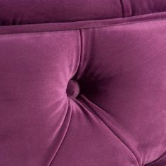 the back end of a purple couch with buttons on it's buttoned cushions