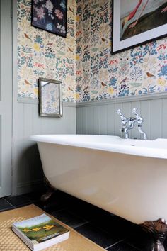 a white bath tub sitting in a bathroom next to a book on top of a rug