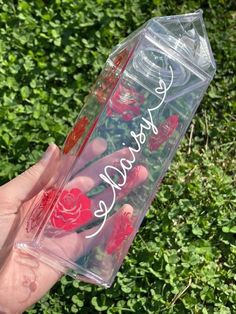 someone holding up a clear plastic case with red roses on it and the words kiss me