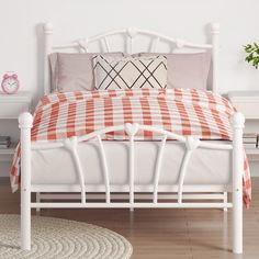 a white bed with an orange and white checkered bedspread on top of it