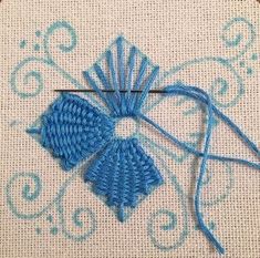 a close up of a cross stitch on a piece of cloth with a blue thread