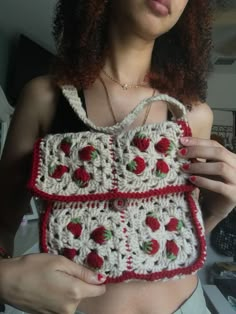 a woman holding a crocheted purse in her hands