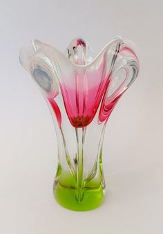 a pink and green vase sitting on top of a white table