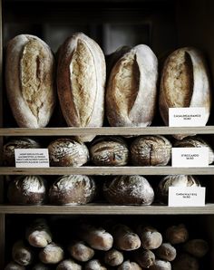 several types of bread on shelves in a bakery