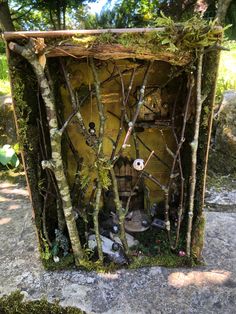 an outdoor shrine made out of branches and mossy material, surrounded by stones and trees