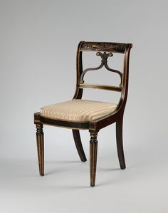 an antique chair with a striped seat and back cushion on the side, against a white background