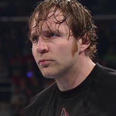 a close up of a person wearing a black t - shirt and standing in front of a crowd