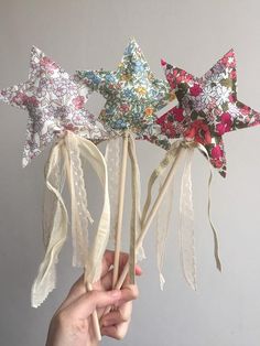 a person is holding up three star shaped lollipops with ribbons on them