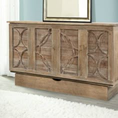 a large wooden cabinet sitting on top of a white rug next to a wall mounted mirror