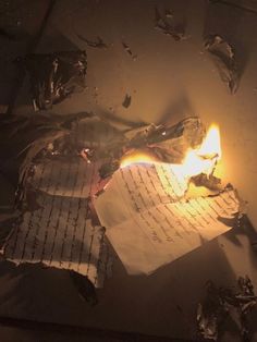 a burning piece of paper on top of a table next to a pile of papers