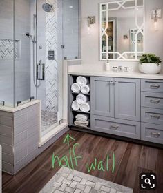 a bathroom with gray cabinets and white towels on the counter, along with a walk in shower