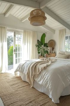 a large bed sitting in a bedroom next to a window covered with white sheets and pillows