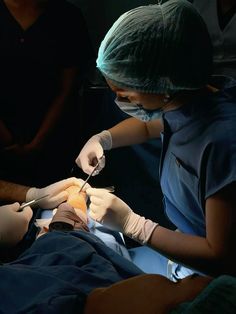 two people in scrubs are performing surgery