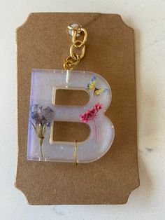 the letter e is made out of glass and has flowers on it, along with a gold chain