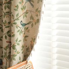 a bird sitting on top of a window sill next to a curtain with birds on it