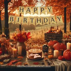 a happy birthday banner with candles and pumpkins on a table in an autumn setting