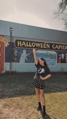 a woman standing in front of a building with a sign on it that says halloween capital